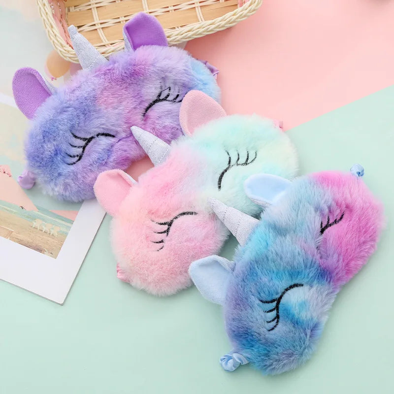 Three colorful unicorn-shaped plush toys on a light green surface.