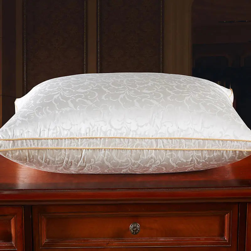 White embroidered pillow on a wooden surface with a dark headboard in the background