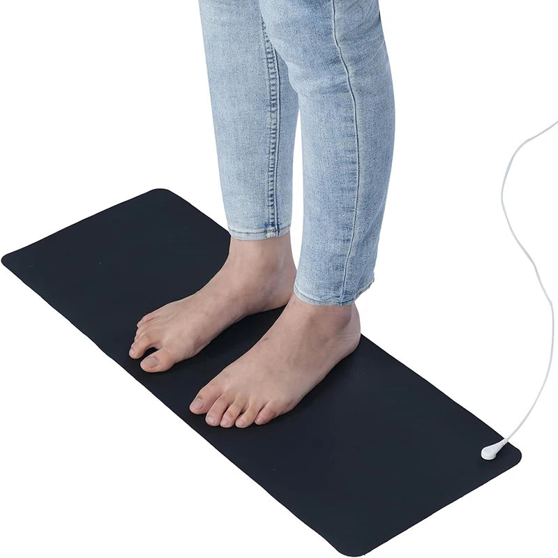 Person standing on a black foot mat with a white cable, wearing light blue jeans.