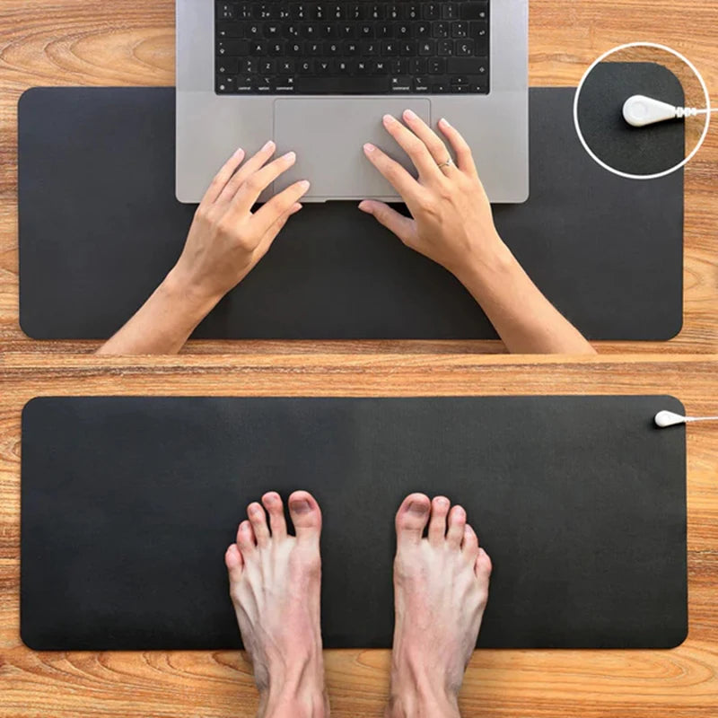 Person using a laptop on a large black desk mat with a smaller mouse pad below.