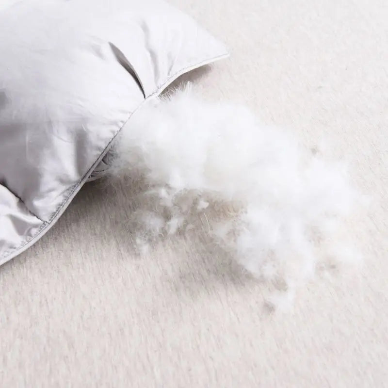 Close-up of a white comforter on a bed with a light background