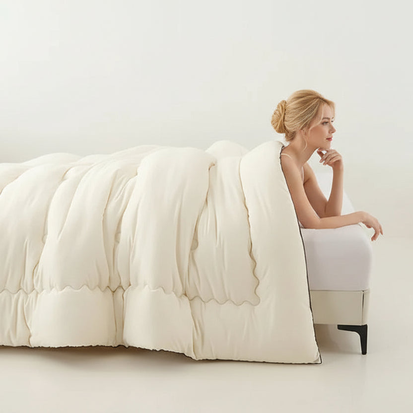 Woman sitting on a bed with a white comforter in a minimalistic room