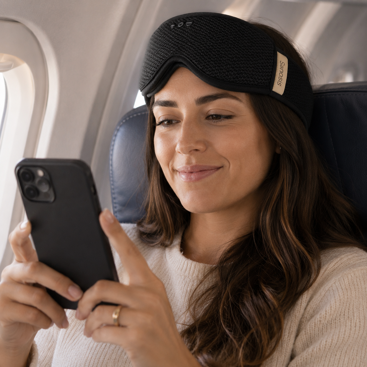 Woman using a smartphone with a sleep mask on during a flight