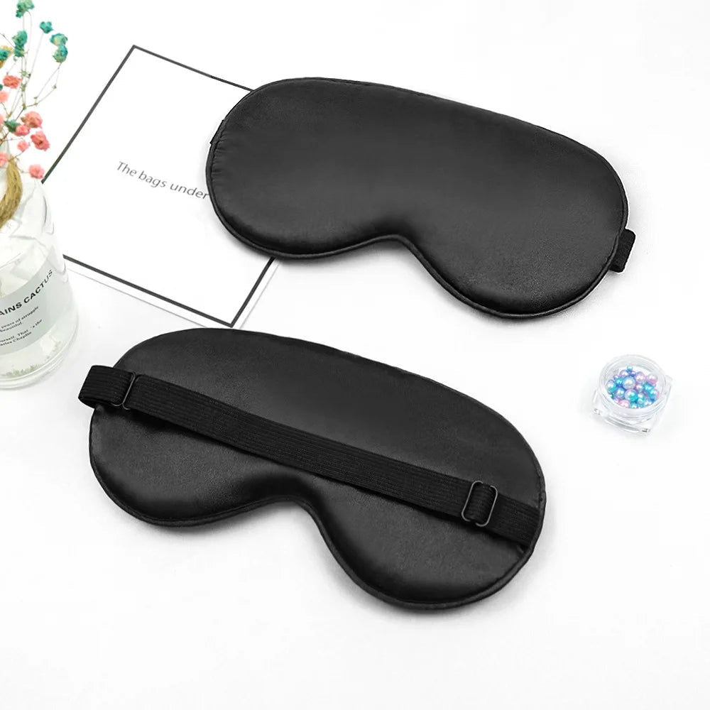 Two black sleep masks on a white surface with a Chanel magazine underneath.