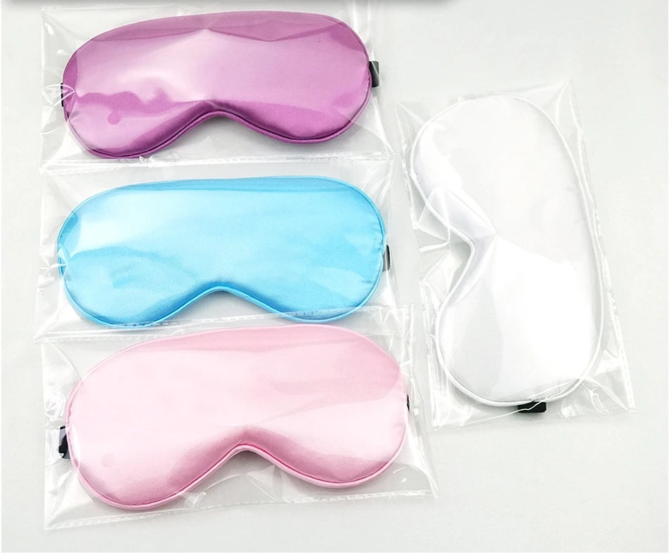 Set of three sleep masks in purple, blue, and pink on a white background