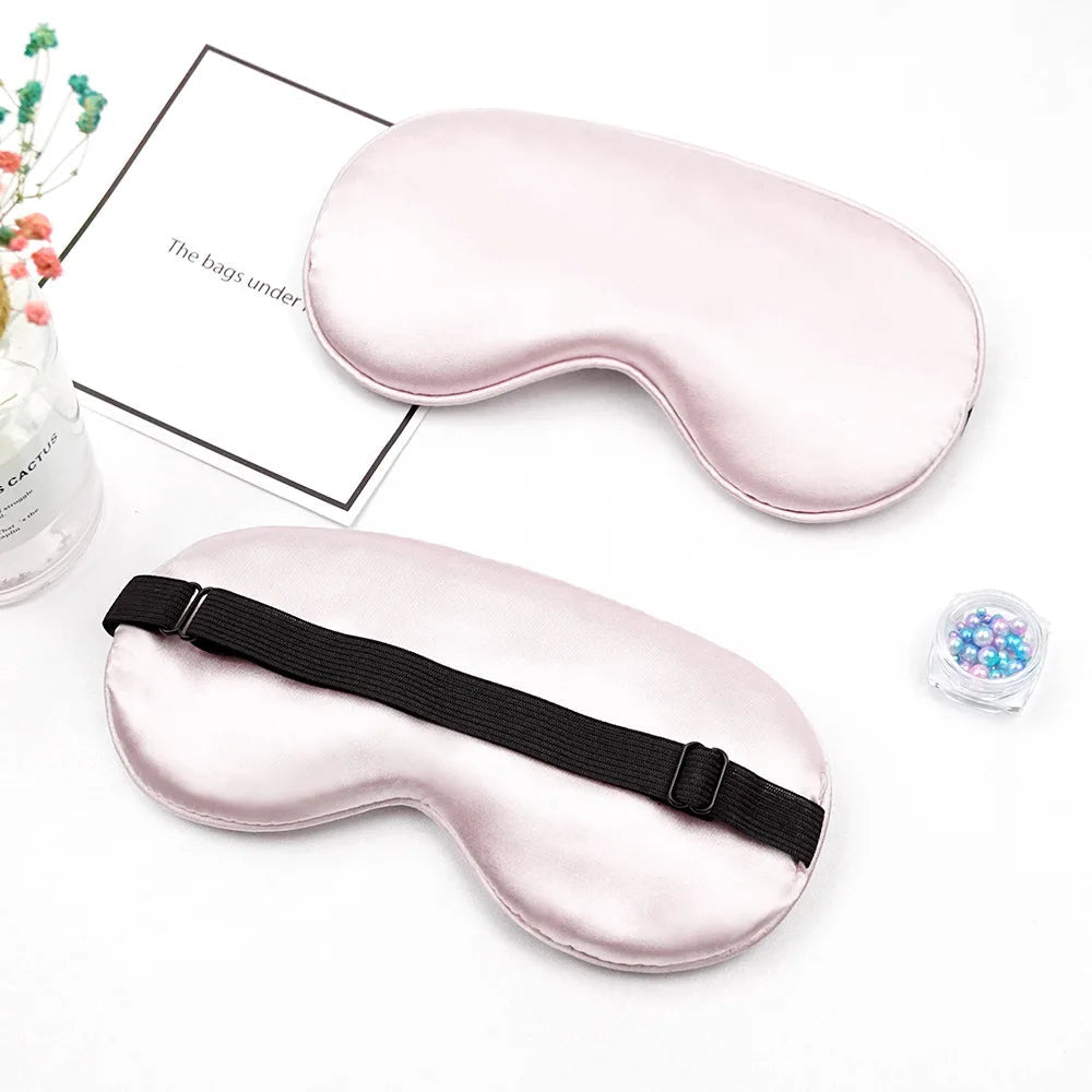 Two silver sleep masks with black straps on a white background.