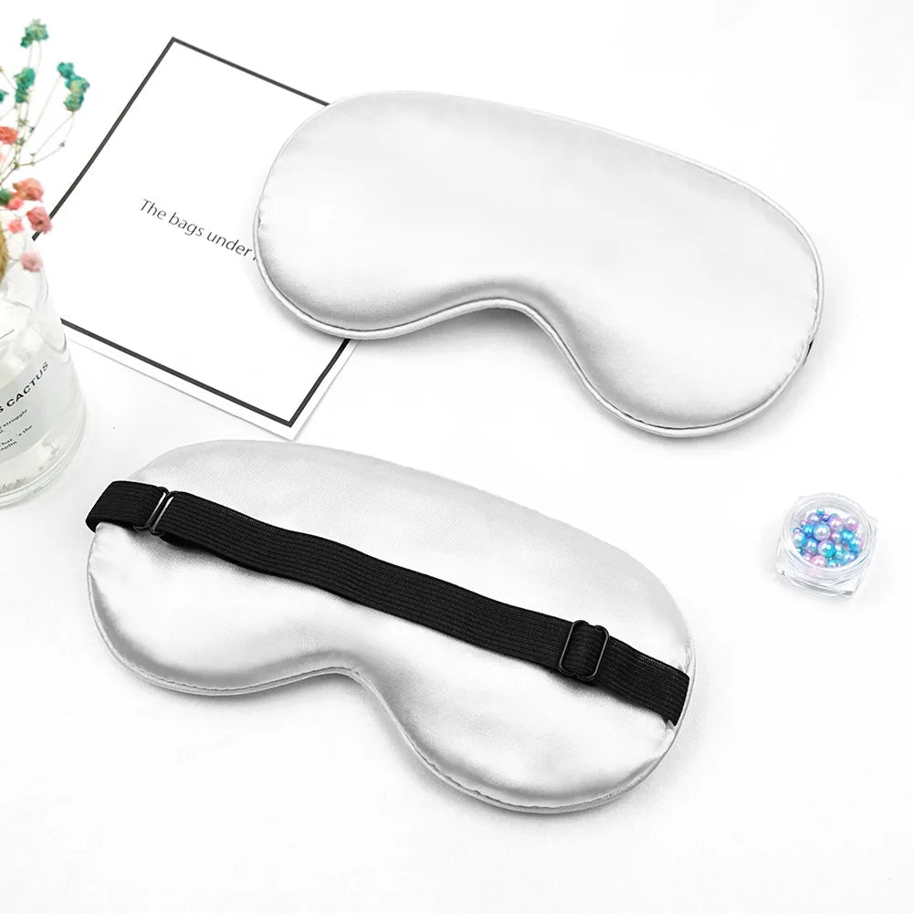 Two white sleep masks with black straps on a white background.