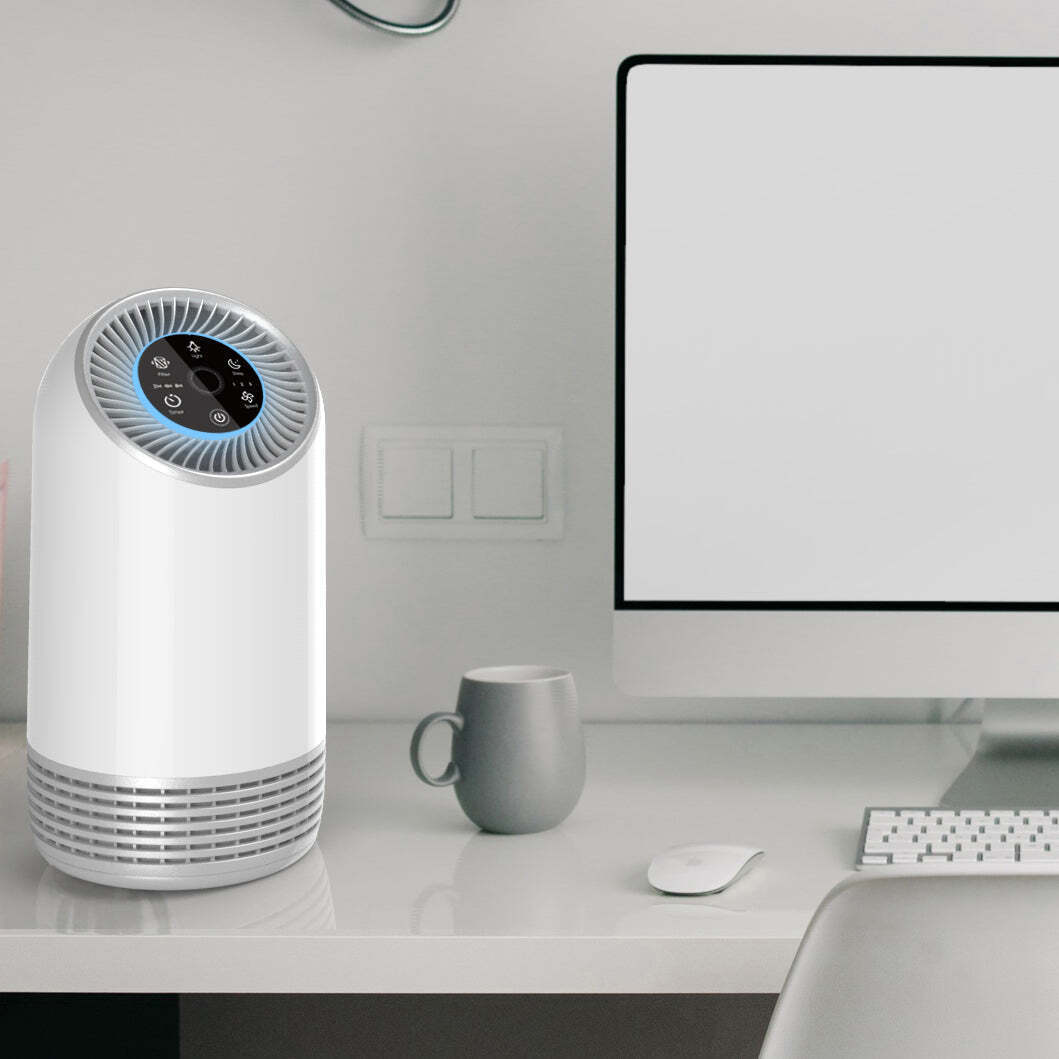 Air purifier on a desk next to a computer monitor and mug
