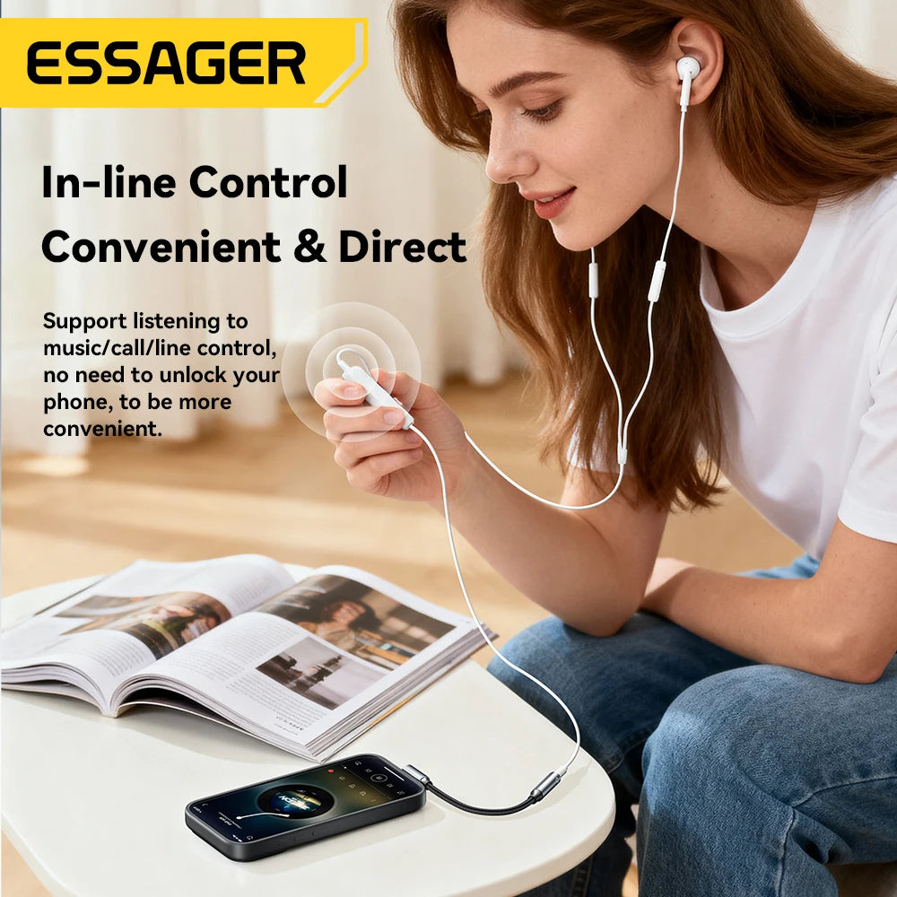 Woman using earphones with in-line control, sitting on the floor next to an open book and phone.